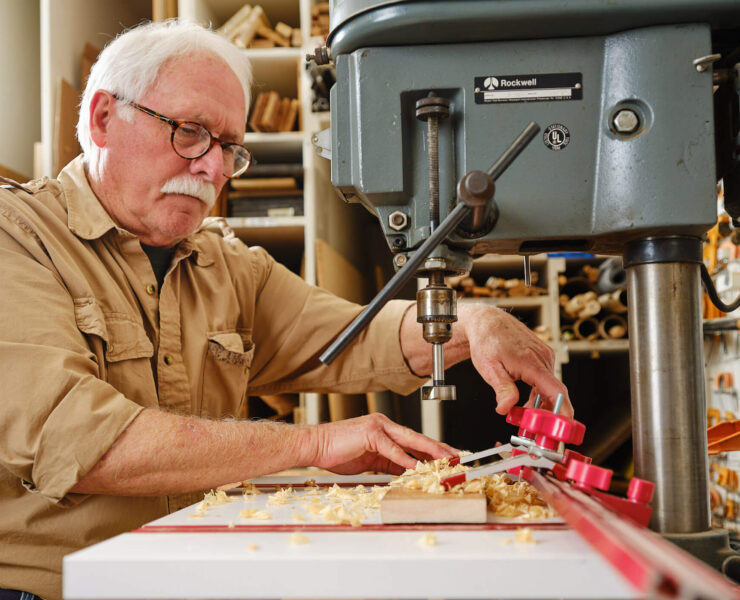 Man using drill press in workshop
