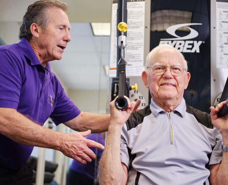 trainer helping man exercise