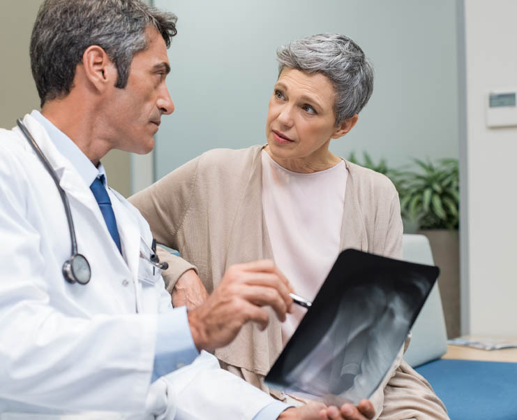 A health care worker reviews an xray with an older woman