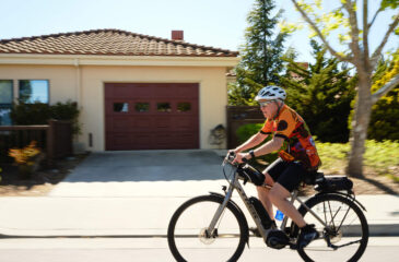 Man bicycling by house with garage