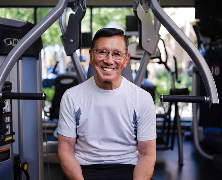 A man sits on a lat machine at the gym