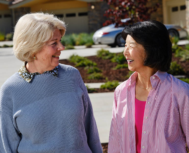 Two mature women look at each other and smile