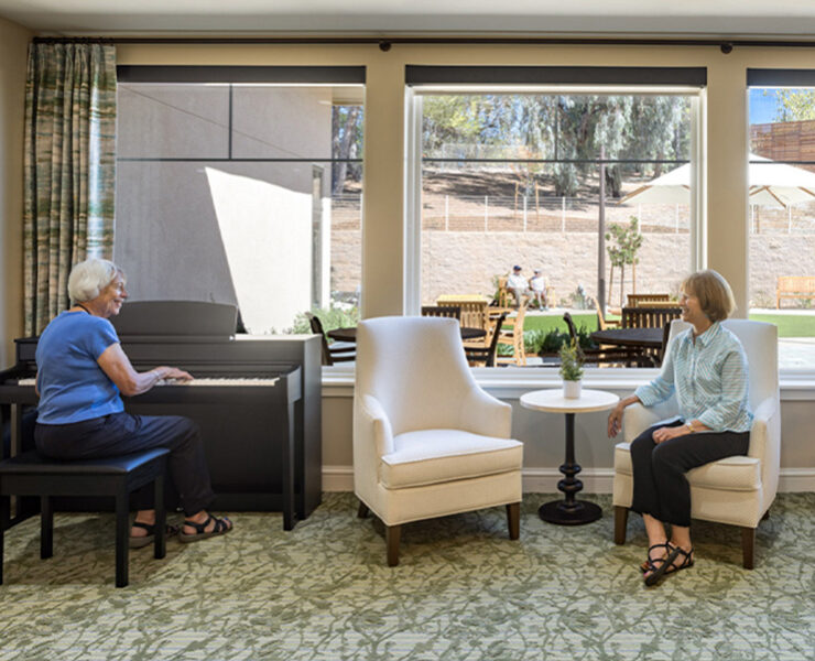 resident playing piano, while another listens to the music